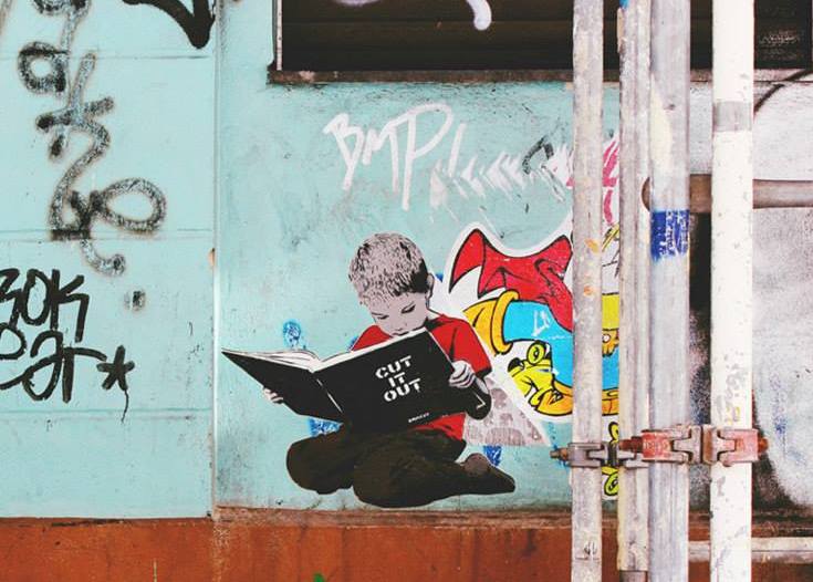 Boy reading a book - street art in Berlin